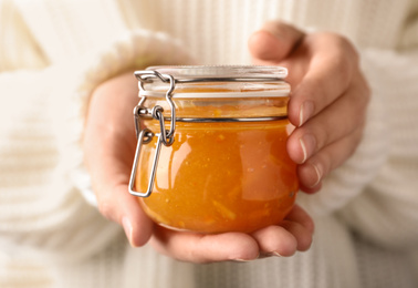 Woman with jar of orange jam, closeup