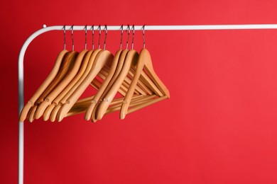 Wooden clothes hangers on metal rack against red background