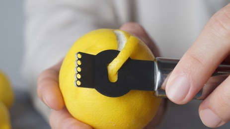 Photo of Man peeling fresh lemon with zester, closeup view