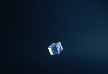 Crystal clear ice cube on dark blue background