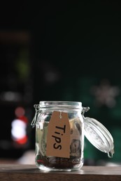 Glass jar with tips on wooden table indoors