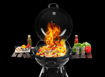 Modern flaming barbecue grill with tasty food on black background