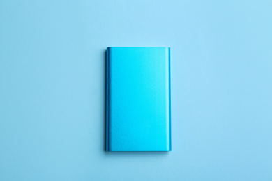 Modern external portable charger on light blue background, top view