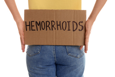 Photo of Woman holding carton sign with word HEMORRHOIDS on white background, closeup