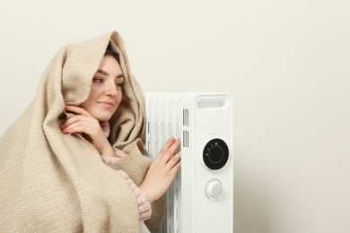 Photo of Young woman warming herself near modern electric heater indoors