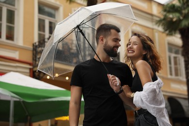 Photo of Young couple with umbrella enjoying time together under rain on city street