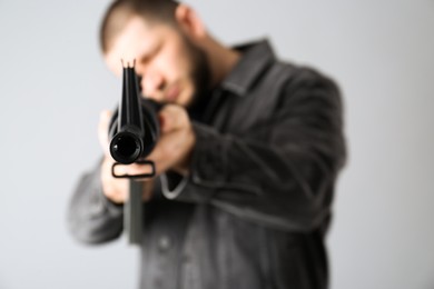 Assault gun. Man aiming rifle against light background, focus on muzzle