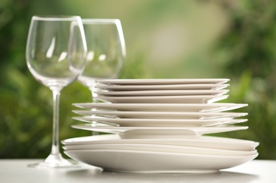 Set of clean dishware and wineglasses on grey table against blurred background