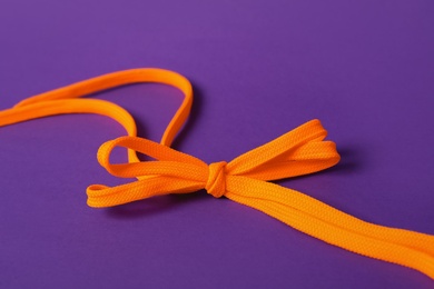 Orange shoe laces tied in bow on purple background