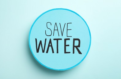 Card with words Save Water on light blue background, top view