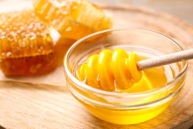 Tasty aromatic honey in bowl on wooden table
