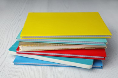Stack of colorful planners on white wooden table