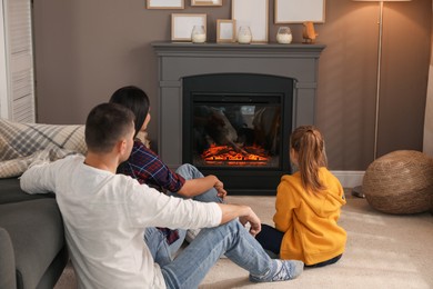 Happy family spending time together near fireplace at home, back view
