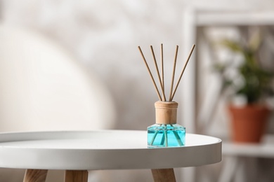 Reed air freshener on white table indoors, space for text