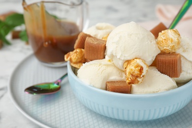 Plate of delicious ice cream with caramel candies and popcorn on table, closeup