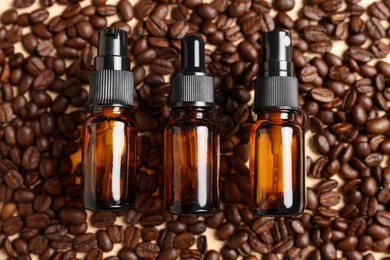 Bottles of organic cosmetic products and coffee beans on beige background, flat lay