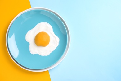 Tasty yogurt with peach imitating fried egg on color background, top view