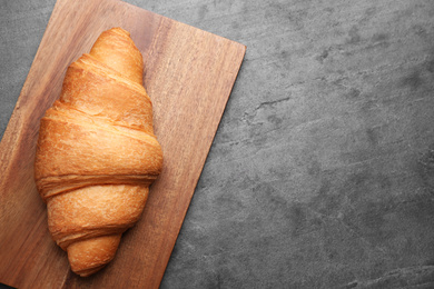 Photo of Tasty fresh croissant on grey table, top view. Space for text