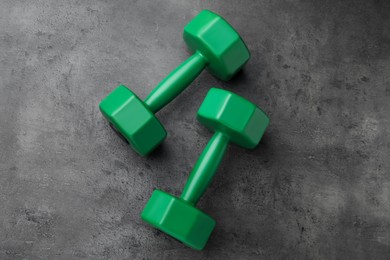 Two green dumbbells on grey table, flat lay
