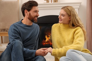 Photo of Lovely couple spending time together near fireplace indoors