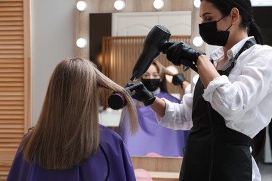 Photo of Professional stylist working with client in beauty salon. Hairdressing services during Coronavirus quarantine