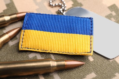 Ukrainian army patch, bullets and ID tags on military camouflage, closeup