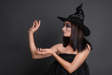 Mysterious witch wearing hat on black background