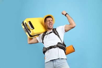 Emotional male tourist with travel backpack and suitcase on turquoise background