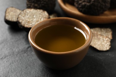 Bowl of truffle oil on grey table, closeup