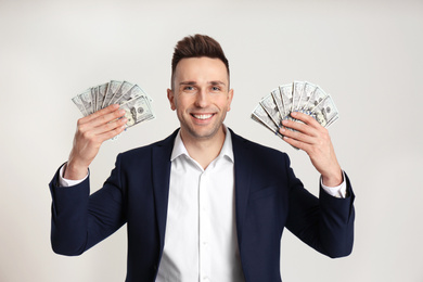 Happy man with cash money on light grey background