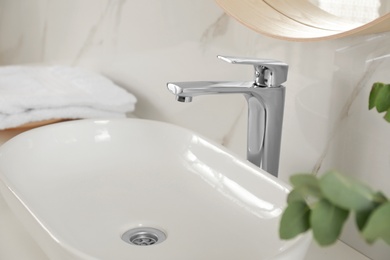 Vessel sink with shiny faucet in bathroom interior