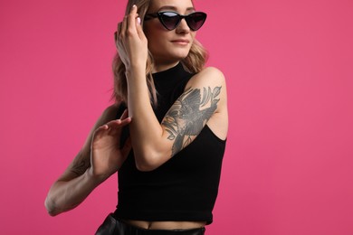 Beautiful woman with tattoos on arms against pink background. Space for text