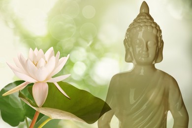 Beautiful ceramic Buddha sculpture and lotus flower on color background