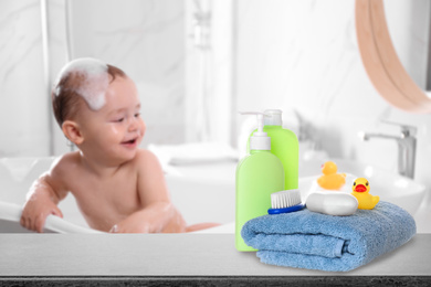 Image of Baby cosmetic products, toys and towel on table in bathroom
