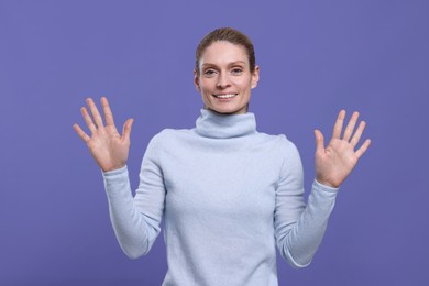 Photo of Woman giving high five with both hands on purple background