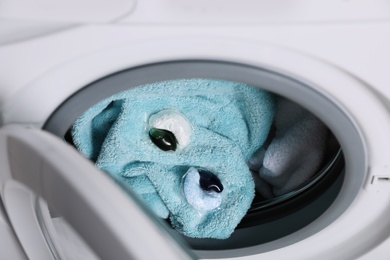 Laundry detergent capsules and towels in washing machine drum, closeup view