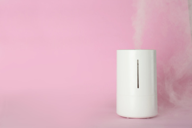 Modern air humidifier on pink background. Space for text