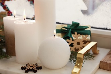 Photo of Beautiful burning candles with Christmas decor on windowsill indoors, closeup