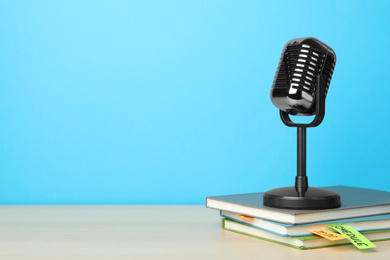 Retro microphone and notebooks on wooden table against light blue background, space for text. Job interview