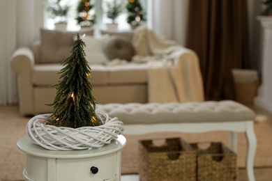 Small decorative Christmas tree on white table in living room. Interior design