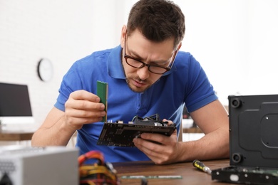 Photo of Male technician repairing computer at table indoors