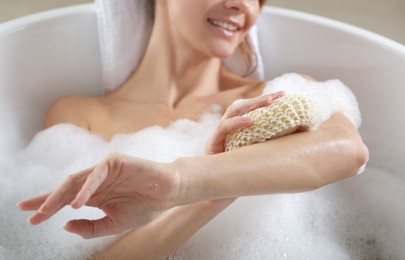Woman rubbing her arm with sponge while taking bath, closeup