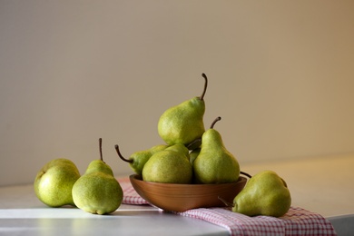 Bowl with fresh ripe pears on white table