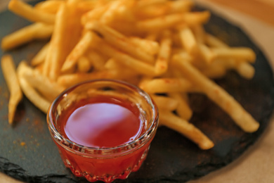 Delicious hot french fries with red sauce served on table, closeup