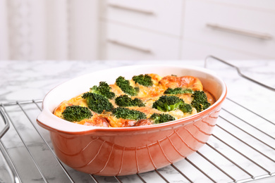 Tasty broccoli casserole in baking dish on cooling rack