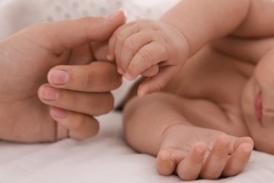 Mother with her cute baby on bed, closeup of hands
