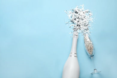 Photo of Flat lay composition with confetti, bottle of champagne and flute glass on light blue background. Space for text
