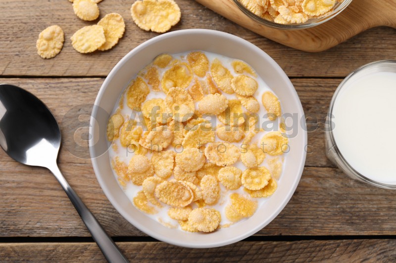 Tasty cornflakes with milk served on wooden table, flat lay