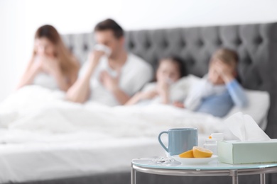 Table with cold remedies and blurred sick family on background