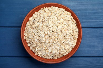 Bowl of oatmeal on blue wooden table, top view